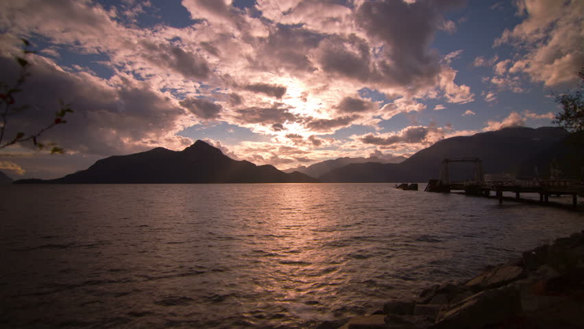 Cloudy Afternoon at Porteau Cove, BC, Canada. Looking at Mountains and Sun Beaming through the Clouds by the Dock of Porteau Cove. Shot in 4k RAW photo sequence