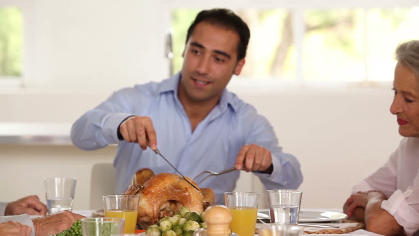 Smiling father carving the holiday turkey at the dinner table