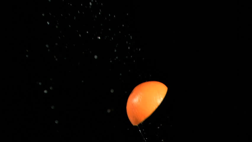 Orange slice rotating in super slow motion against black background