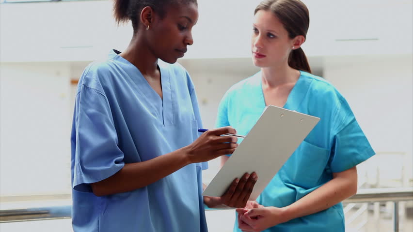 Female nurse and intern holding a clipboard in hospital