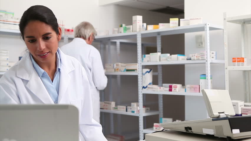 Smiling pharmacist handing paper to a customer in a hospital
