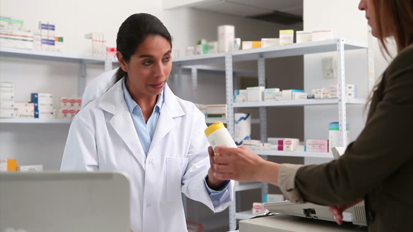 Smiling female pharmacist handing drugs to a customer in a hospital