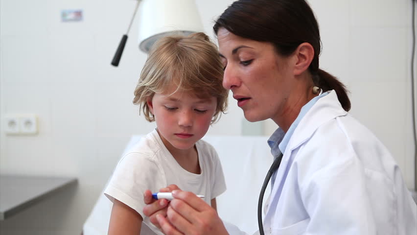 Doctor taking temperature of a child in examination room