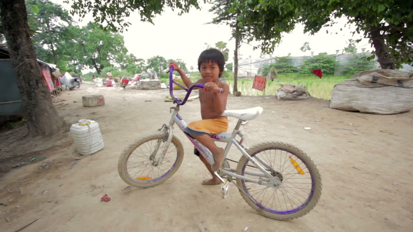 Cambodian boy in slum on bike