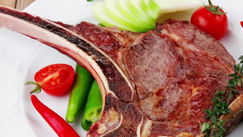 savory : roasted beef spare rib on white dish with cutlery thyme pepper and tomato on wooden table