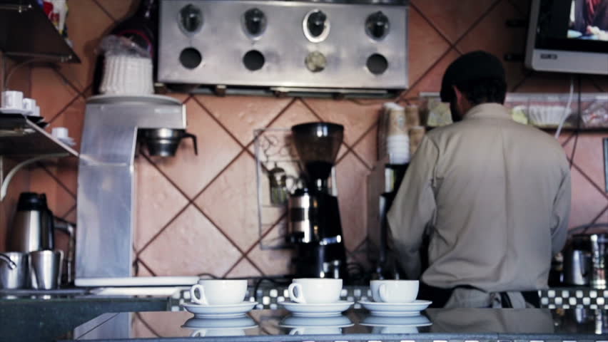 Male barista finishing two cups of espresso in coffee machine 