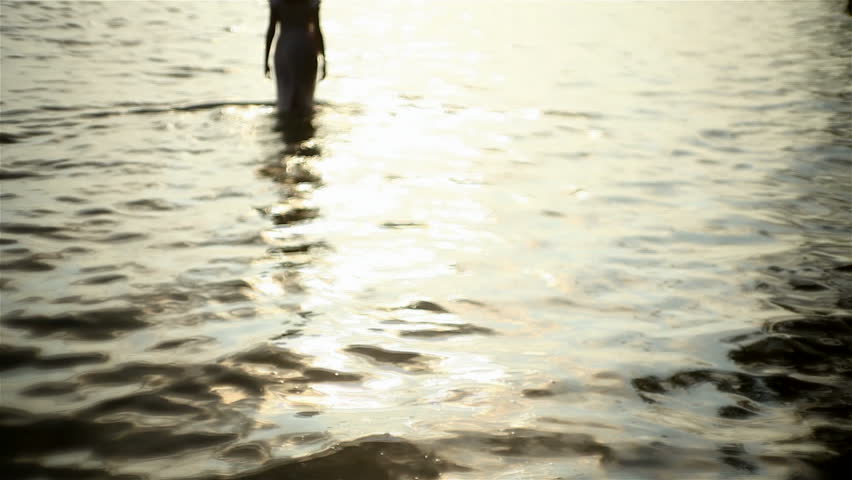 girl walking in from the sea at sunset