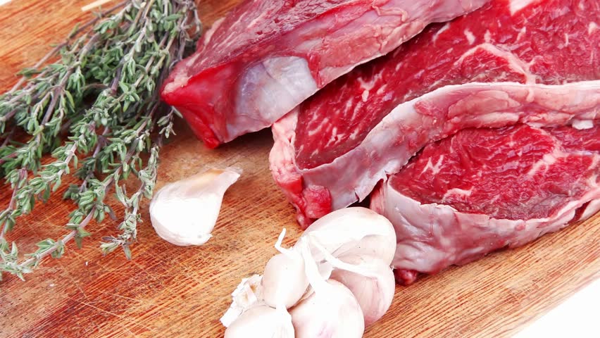 fresh raw beef meat fillet flesh with peppercorn and thyme ready to grill on wood figured old style board isolated over white background