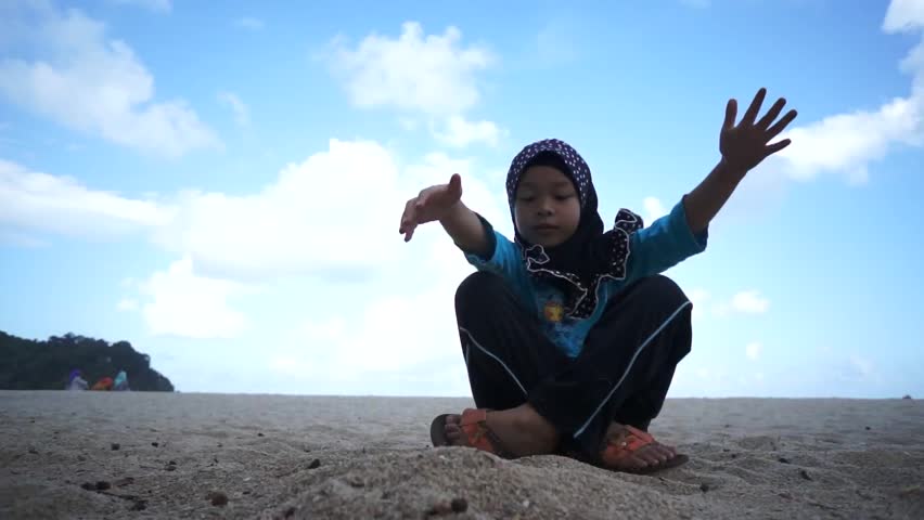 Beautiful muslim girl wearing scarf drop sand on the ground from hand