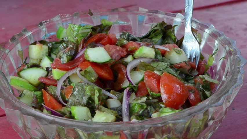 Salad made of tomatoes cucumber red onion lettuce leaves mixed in glass dish. Healthy ecologic food nutrition.