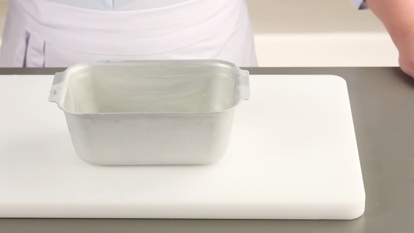 Banana bread dough being transferred to a loaf tin
