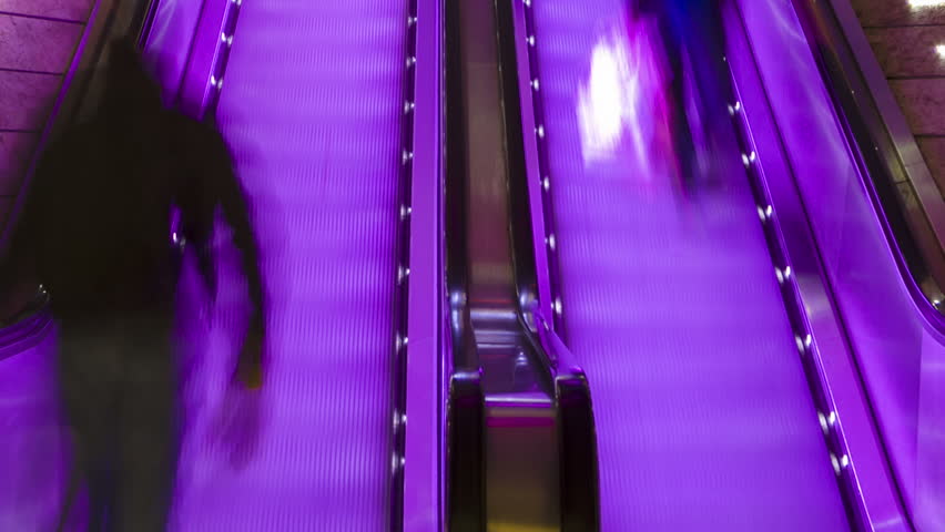 Timelapse of blurred shoppers riding an escalator at a shopping mall