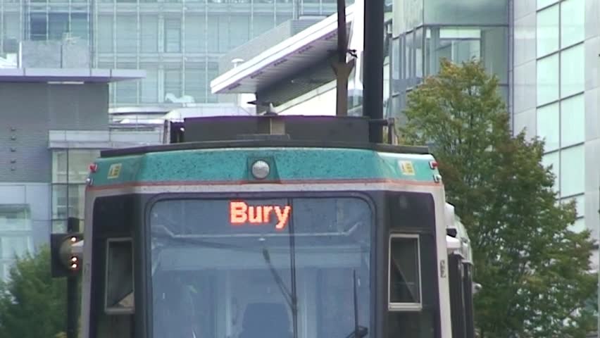 MANCHESTER, ENGLAND - CIRCA 2011: Pedestrians pass after a Bury bound Metrolink Tram departs.