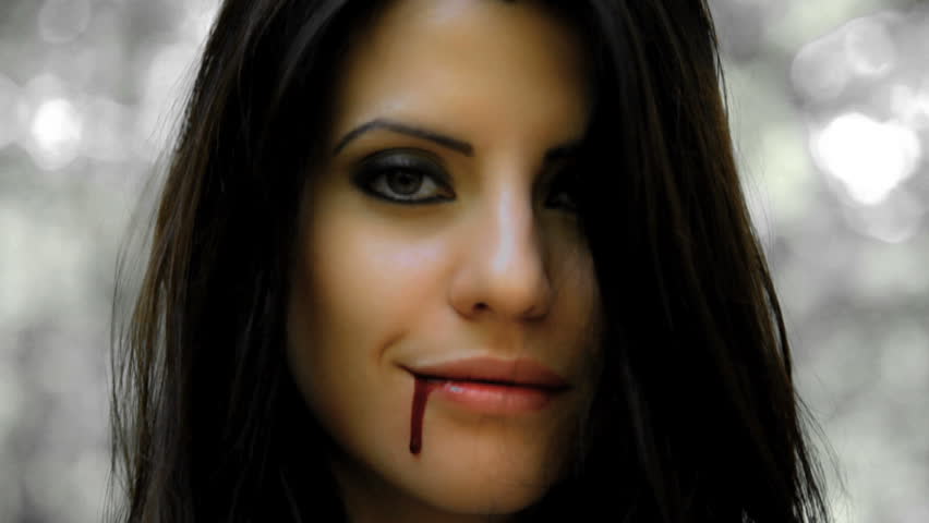 Beautiful vampire woman smiling with blood on her face after bite/A vampire can smile to die for