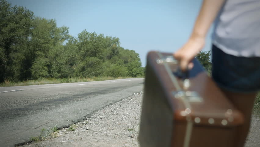 Young woman with guitar on the road and her vintage baggage