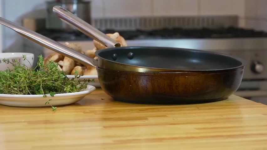 Pan over kitchen utensils, plates and bowls with freshly cut ingredients, ending at a chef, seasoning a large roast (haunch of venison)