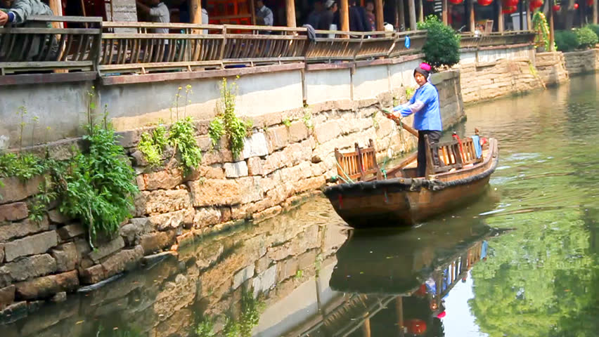 LUZHI - APRIL 29: Woman rowing a boat through a canal on April 29, 2011, in Luzhi, China. Luzhi is the first water town in China and attracts travelers from all over the world enjoy the tranquility.