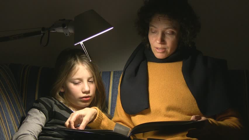 Mother and daughter on sofa reading book
