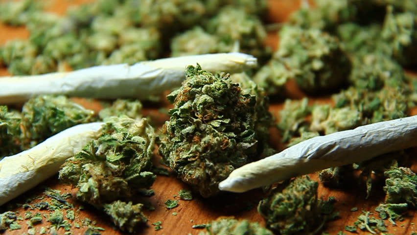 Cannabis and Smoke 2. Nuggets of marijuana and rolled joints on a table, puffs of smoke being blown.