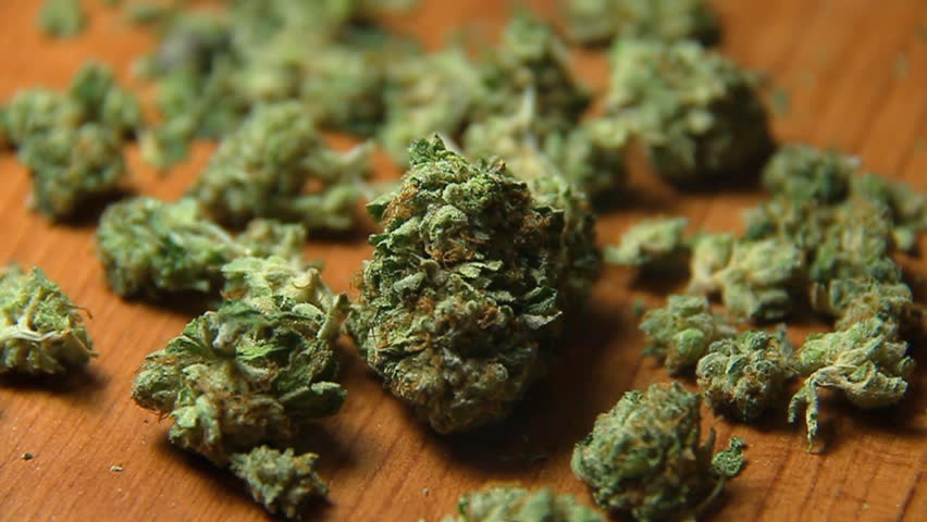 Cannabis and Smoke 1. Nuggets of marijuana on a table, puffs of smoke being blown.