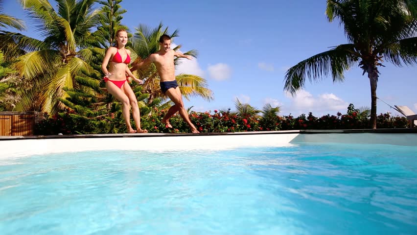Young couple jumping in swimming pool