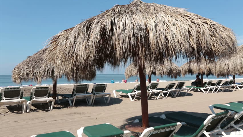 Beach tropical vacation umbrella lounge Mexico. Nuevo Vallarta, near Puerto Vallarta, Mexico luxury resort hotel complex. Beach with tropical palm umbrellas, lounge chairs sunbathing and recreation.