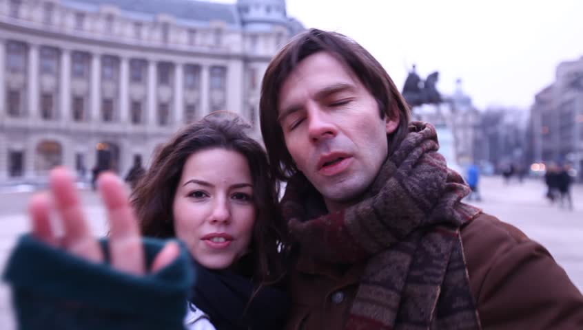Young adult couple gets caught by paparazzi and runs from camera.
