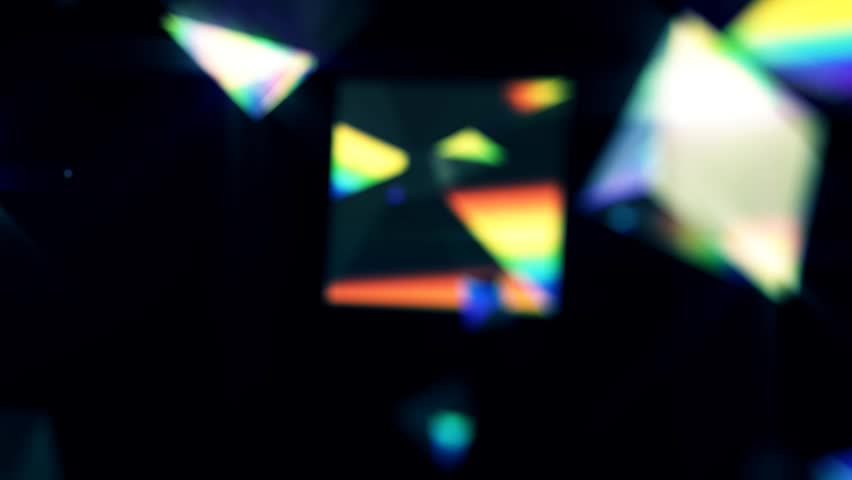 Blurred triangle prisms float with rainbows on black background