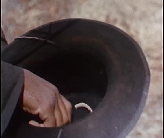 Man rigging trigger on rifle to tree branch with rope