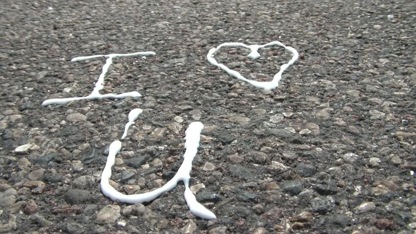 White glue is applied to blacktop road reading I love you, with love represented as a heart symbol, and you with letter u.