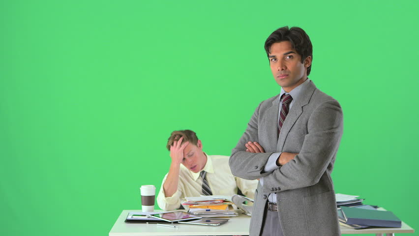 Confident businessman standing in front of distressed colleague on greenscreen
