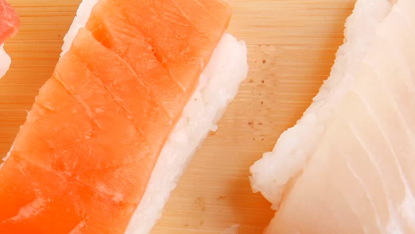 Japanese Cuisine - Set of Tuna (maguro) Salmon (sake) and Eel (unagi) Nigiri Sushi with Wasabi on wooden plate  hidef intro slow motion