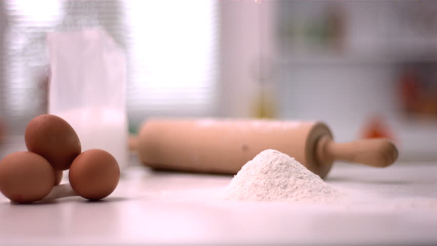 Flour sprinkling on kitchen counter with baking tools in slow motion