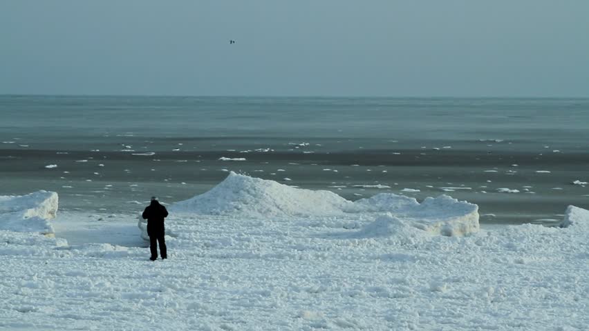 Man looking at the winter sea from the frozen coast. Black sea coast, Bulgaria.