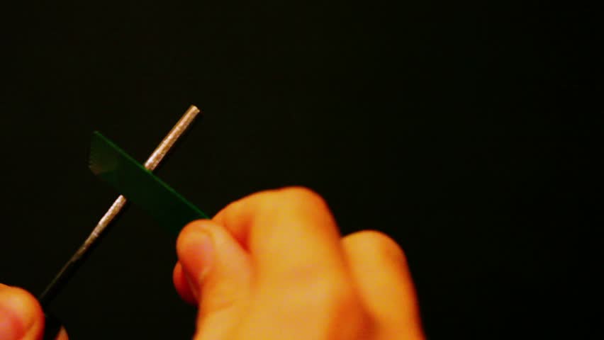Hand holds metal stick and casts sparks with light flashes, closeup