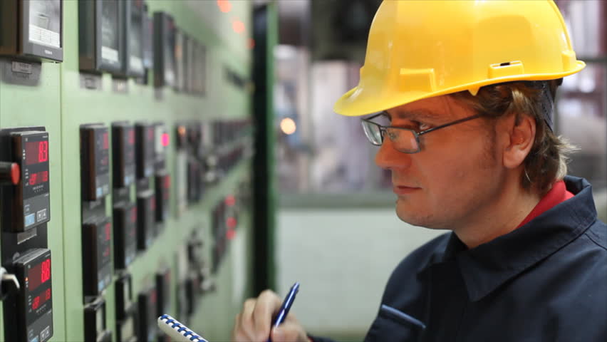 The worker writes the results of measuring devices in the control room at the factory. Shallow Doff, selective focus.