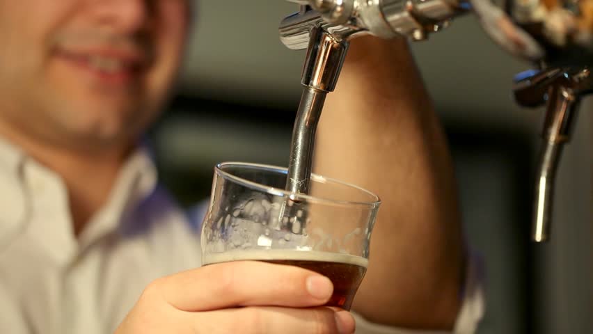 Barman filling a glass of beer in a pub