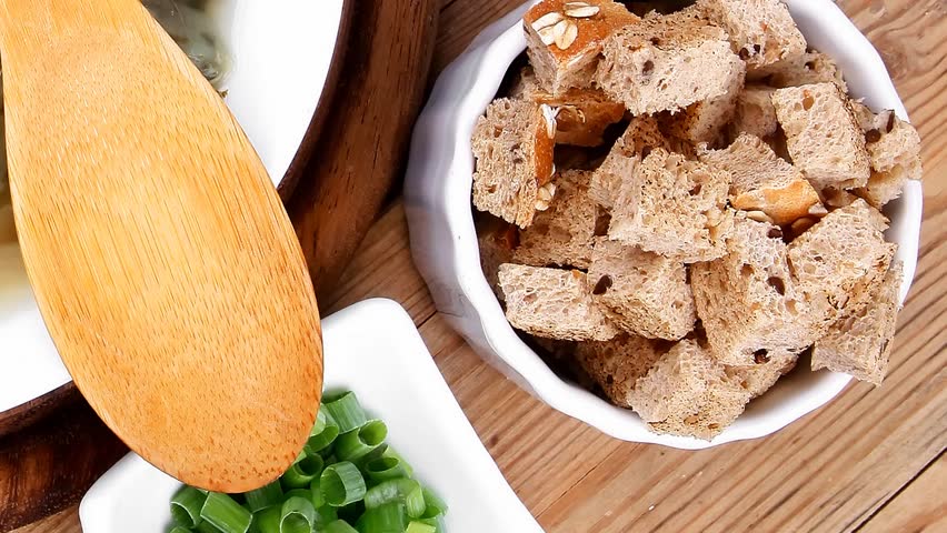 hot fresh diet vegetable soup with rye bread crackers over wood table on stand