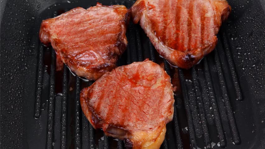 fresh grilled bloody beef steaks on black grill plate hidef slow motion intro