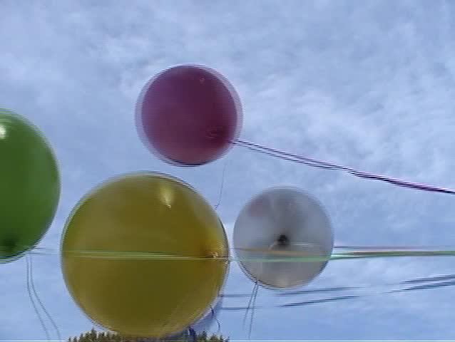 5 helium balloons float in the wind against a blue spring sky