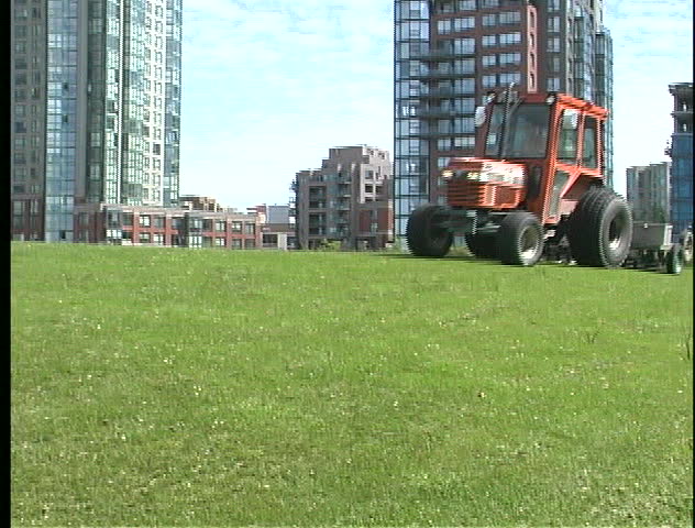 Motorized grass cutter trims lawn in Vancouver, BC's David Lam park.