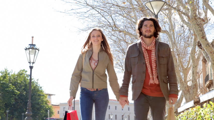 Young attractive couple walking together in the city while on vacation during a sunny day.