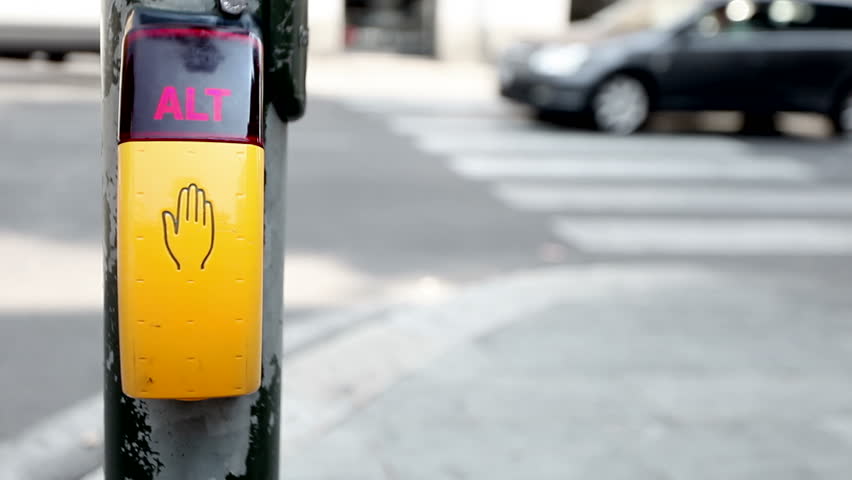 a hand of a lady pushes an alt button while cars are running in the terrible traffic of the city, near a zebra crossing.
