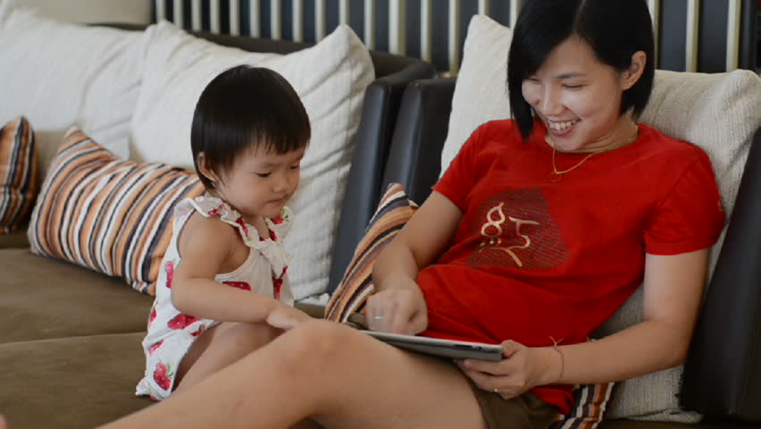 little girl playing tablet with her mother