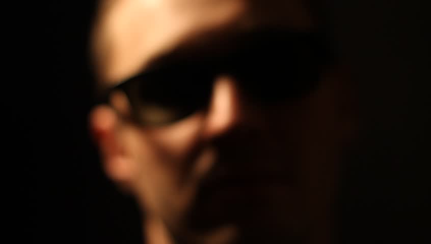 Slow tracking shots of a young handsome man on a black backdrop. Serious, angry, and neutral facial expressions.