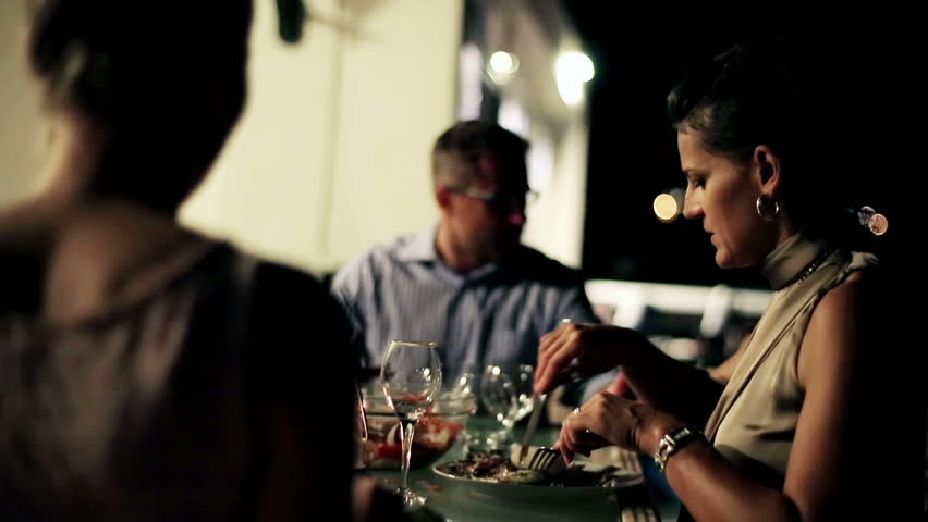 Group of friends celebrating dinner on the terrace at night, steadycam shot
