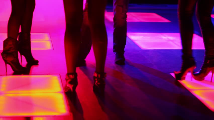 Three women and one man dance in night club, only legs are visible