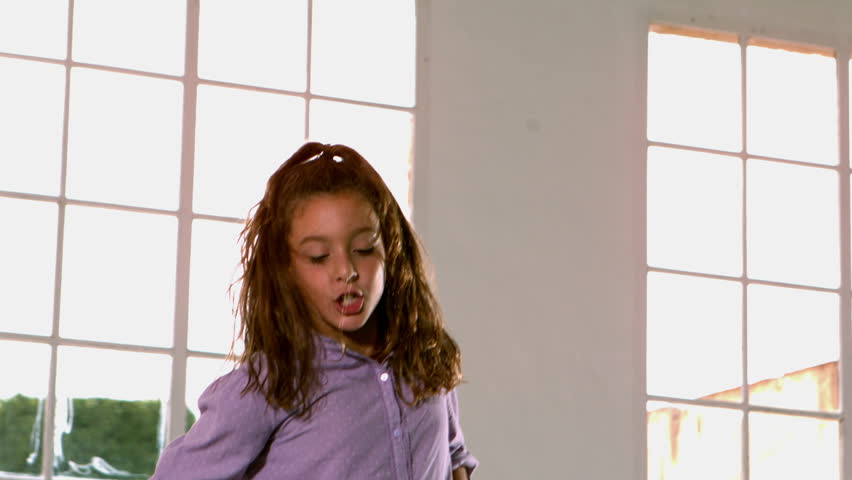 Happy girl jumping up and down in front of window in slow motion