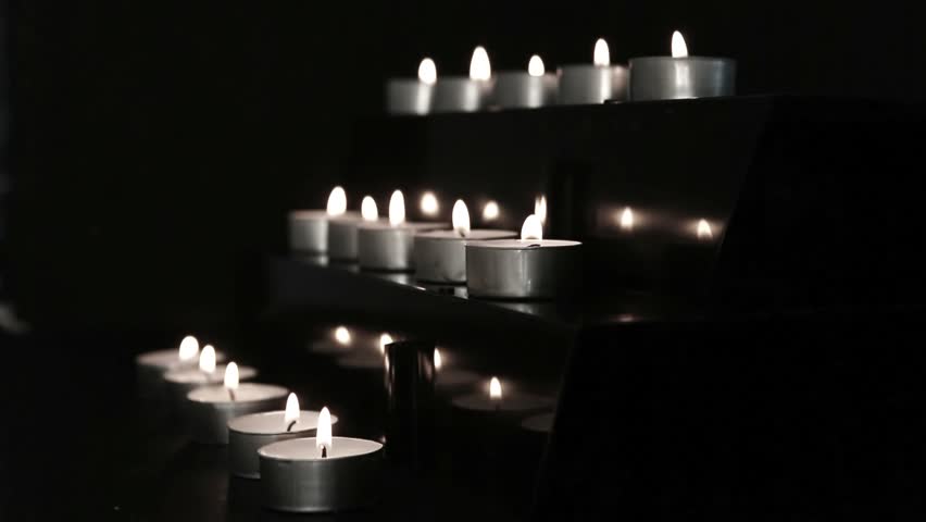 Candles at the alter flickering and being blown out in black and white