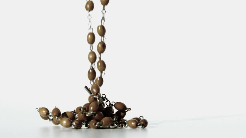 Rosary beads falling onto a white surface in slow motion